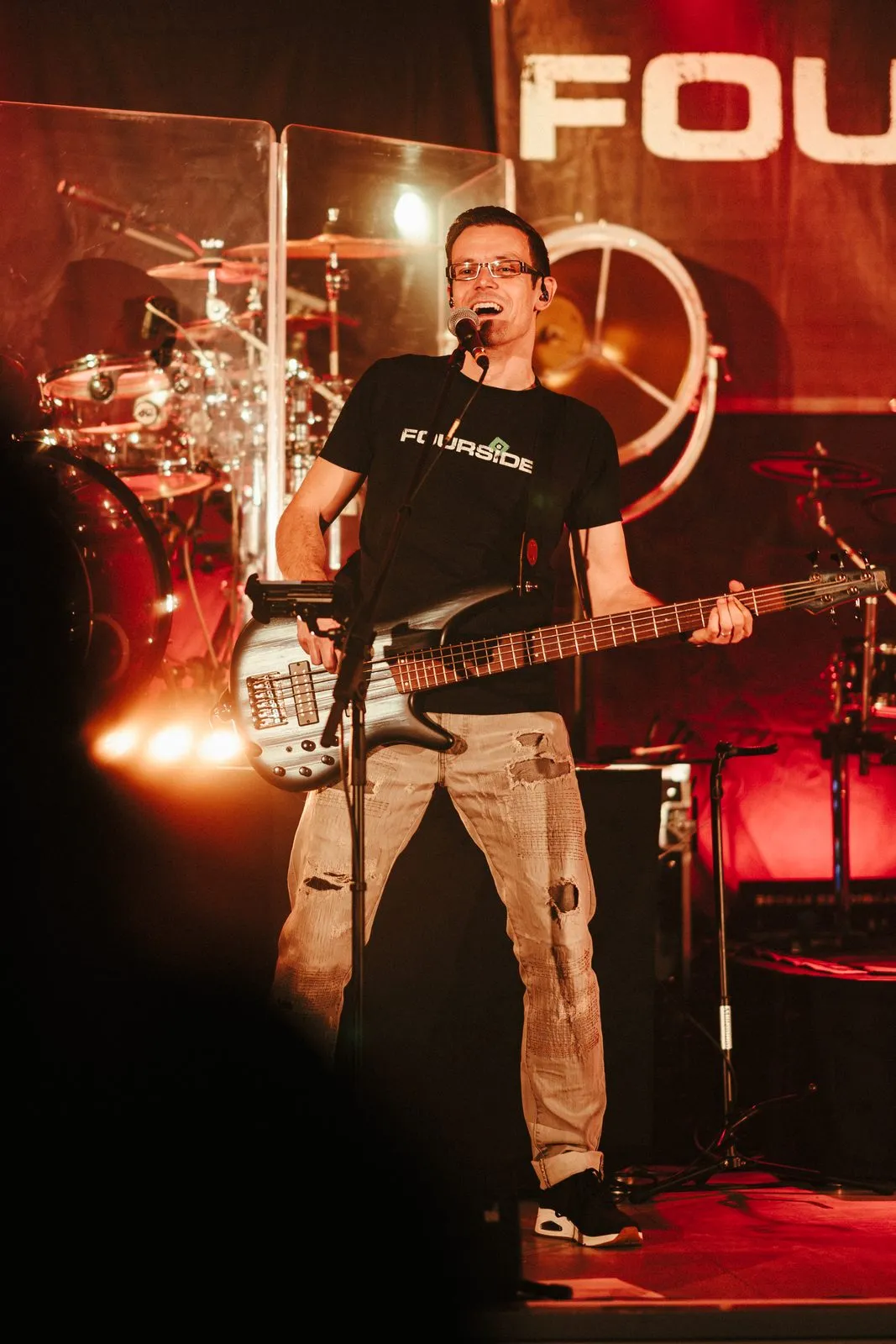 Foursides: Bassist am Mikrofon im roten Bühnenlicht