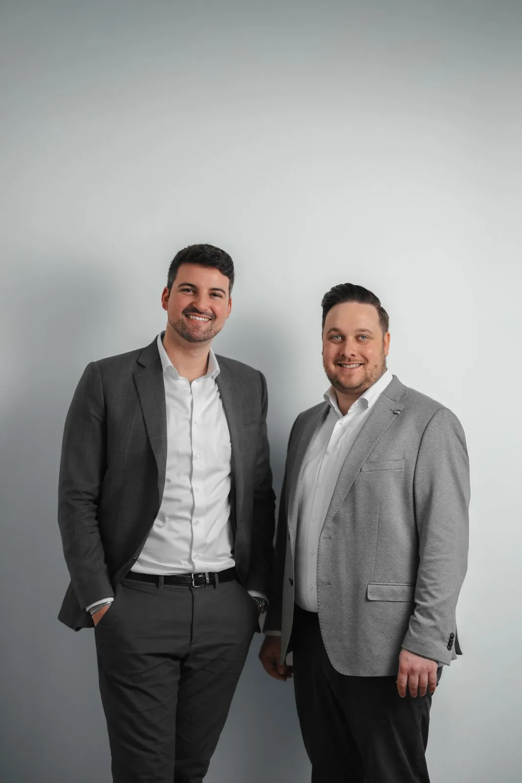Engel & Völkers: Teamportrait zweier Makler vor hellem Hintergrund